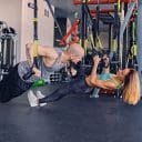 shaved-head-athletic-male-slim-brunette-female-exercising-with-trx-straps-gym-club-1-scaled
