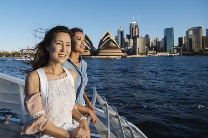 Friends enjoying coastal views onboard a Captain Cook Cruises whale watching tour off Sydney Heads.